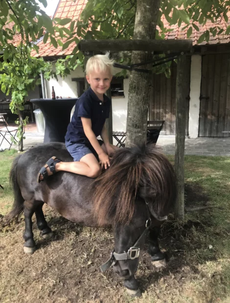 Jongetje zit op zwarte shetland pony