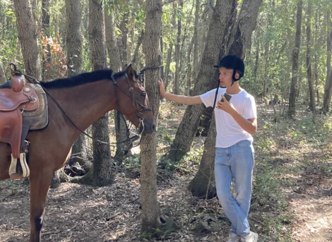 Jongeman staat naast zijn paard in het bos