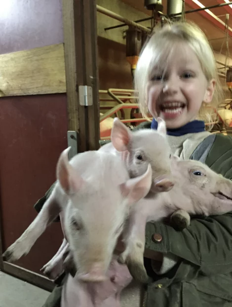 Meisje poseert trots met drie biggetjes in haar armen